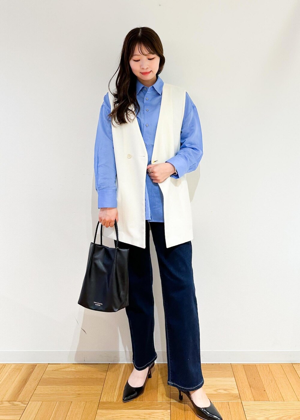 ブラック系のトートバッグ、ホワイト系のベスト、ブルー系のシャツ/ブラウスを着用したレディースの夏コーディネートの2枚目の写真
