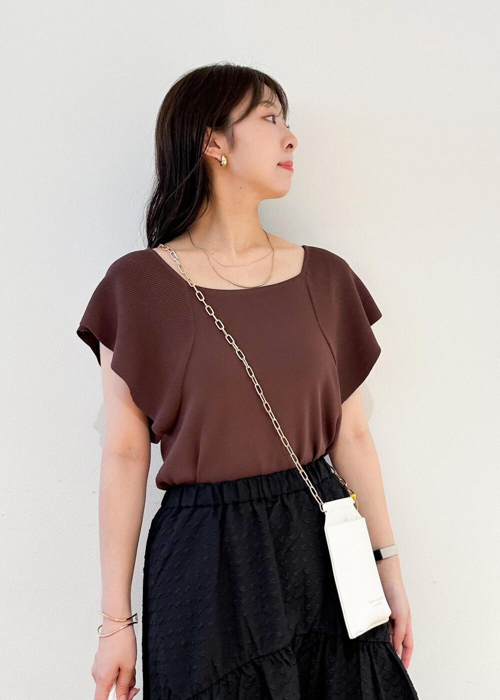 ホワイト系のショルダーバッグ、ブラウン系のニット/セーター、ブラック系のスカートを着用したレディースの夏コーディネートの5枚目の写真