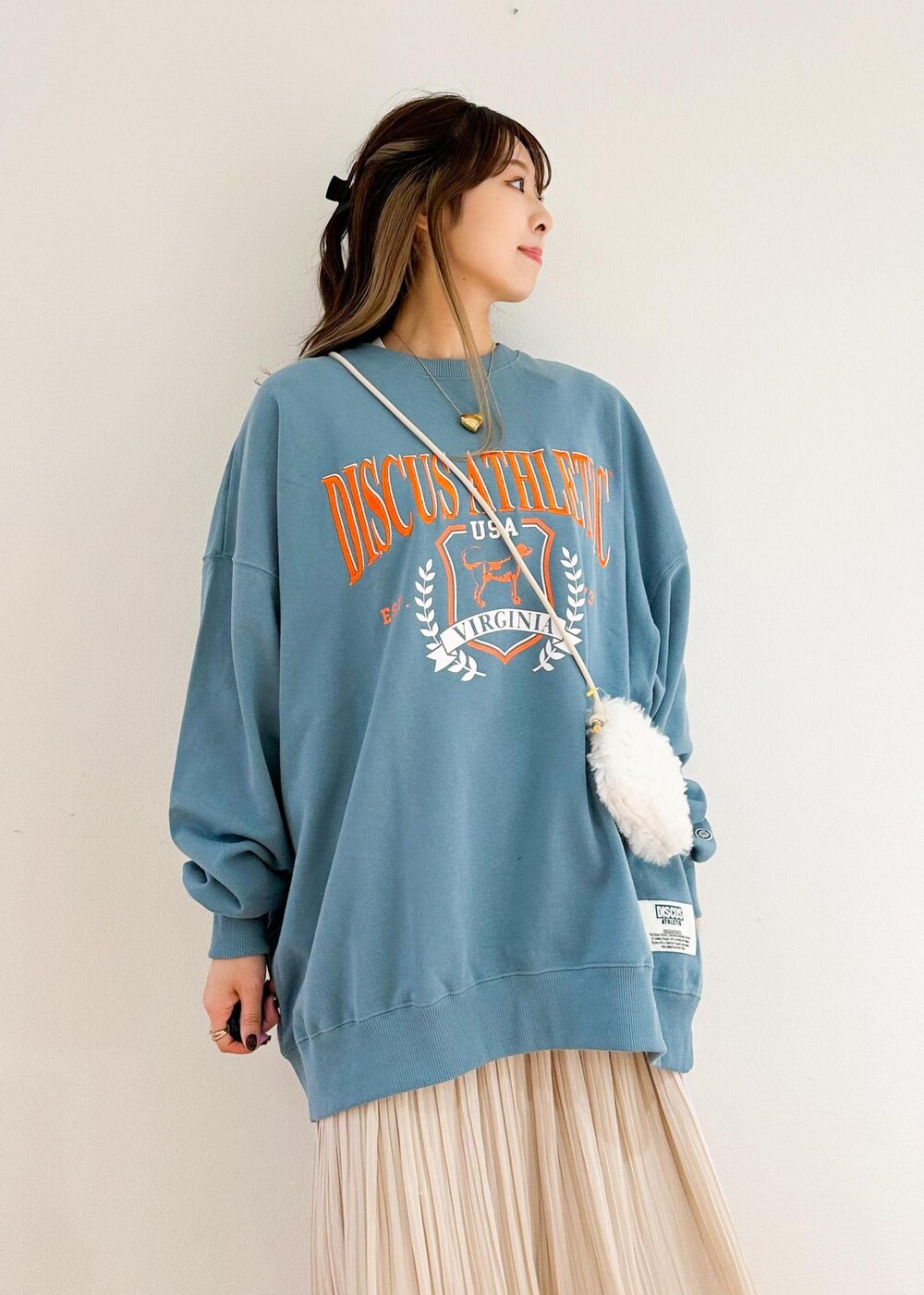 ベージュ系のスカート、ホワイト系のショルダーバッグ、グリーン系のスウェットを着用したレディースの秋コーディネートの4枚目の写真