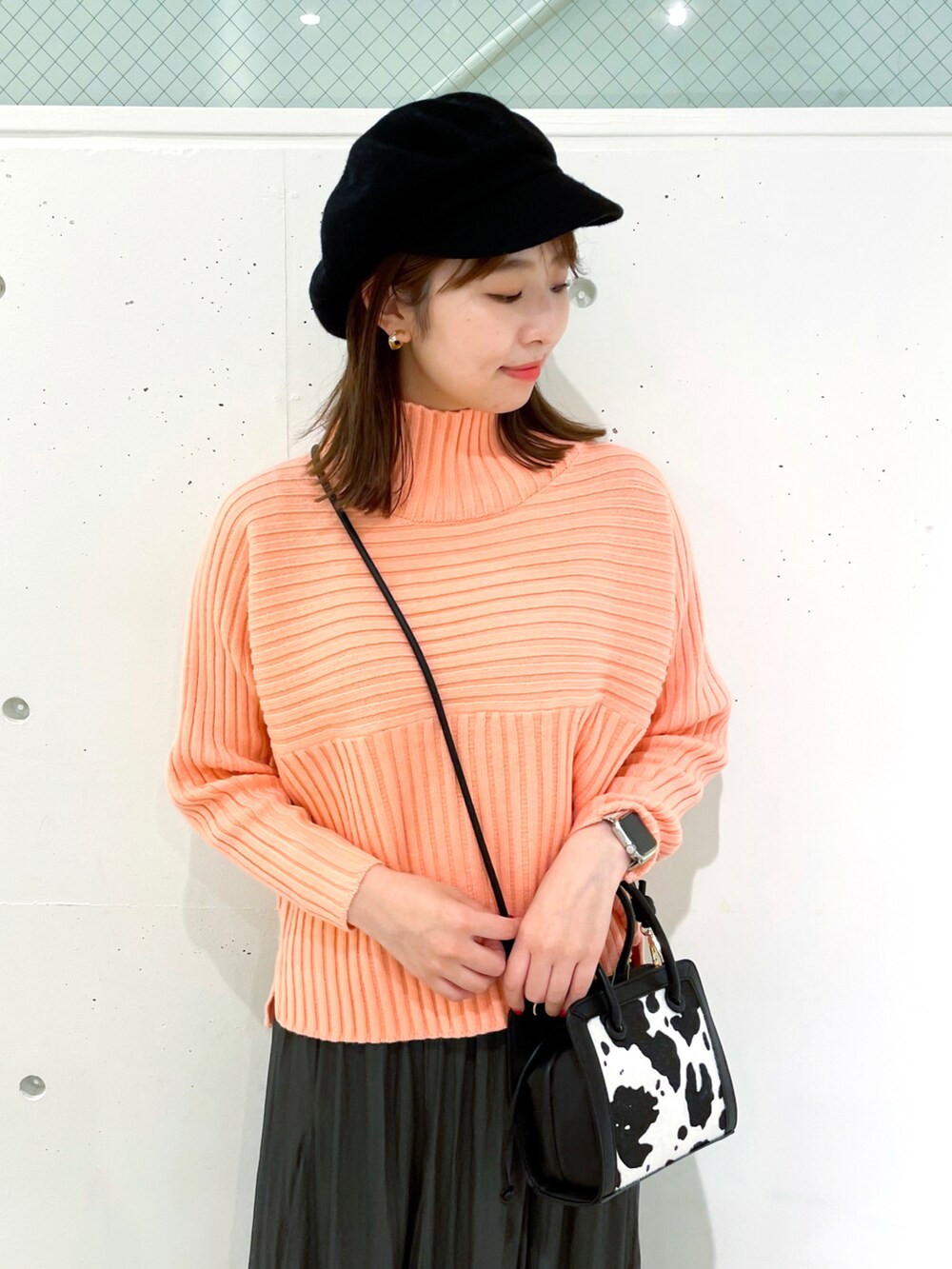 ピンク系のニット/セーター、グレー系のスカート、ブラック系のブーツを着用したレディースの冬コーディネートの3枚目の写真