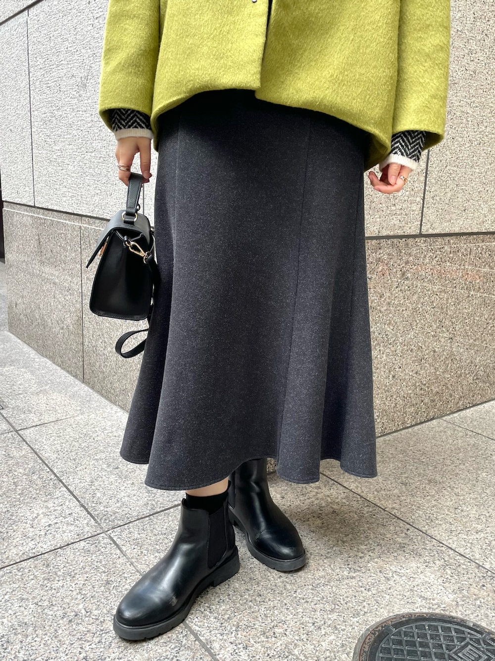 イエロー系のその他アウター、ブラック系のニット/セーター、ブラック系のショルダーバッグを着用したレディースの冬コーディネートの5枚目の写真