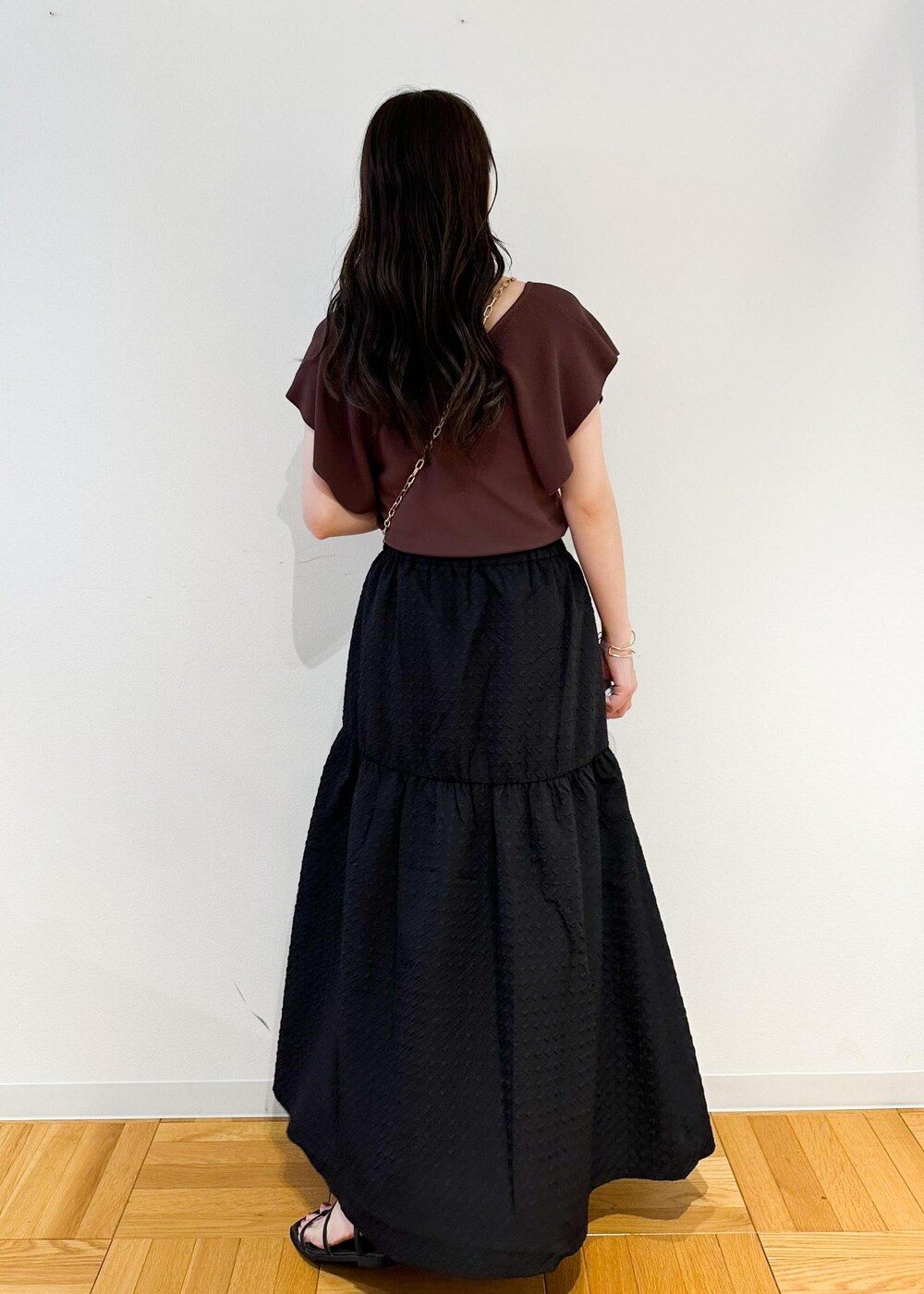 ホワイト系のショルダーバッグ、ブラウン系のニット/セーター、ブラック系のスカートを着用したレディースの夏コーディネートの4枚目の写真