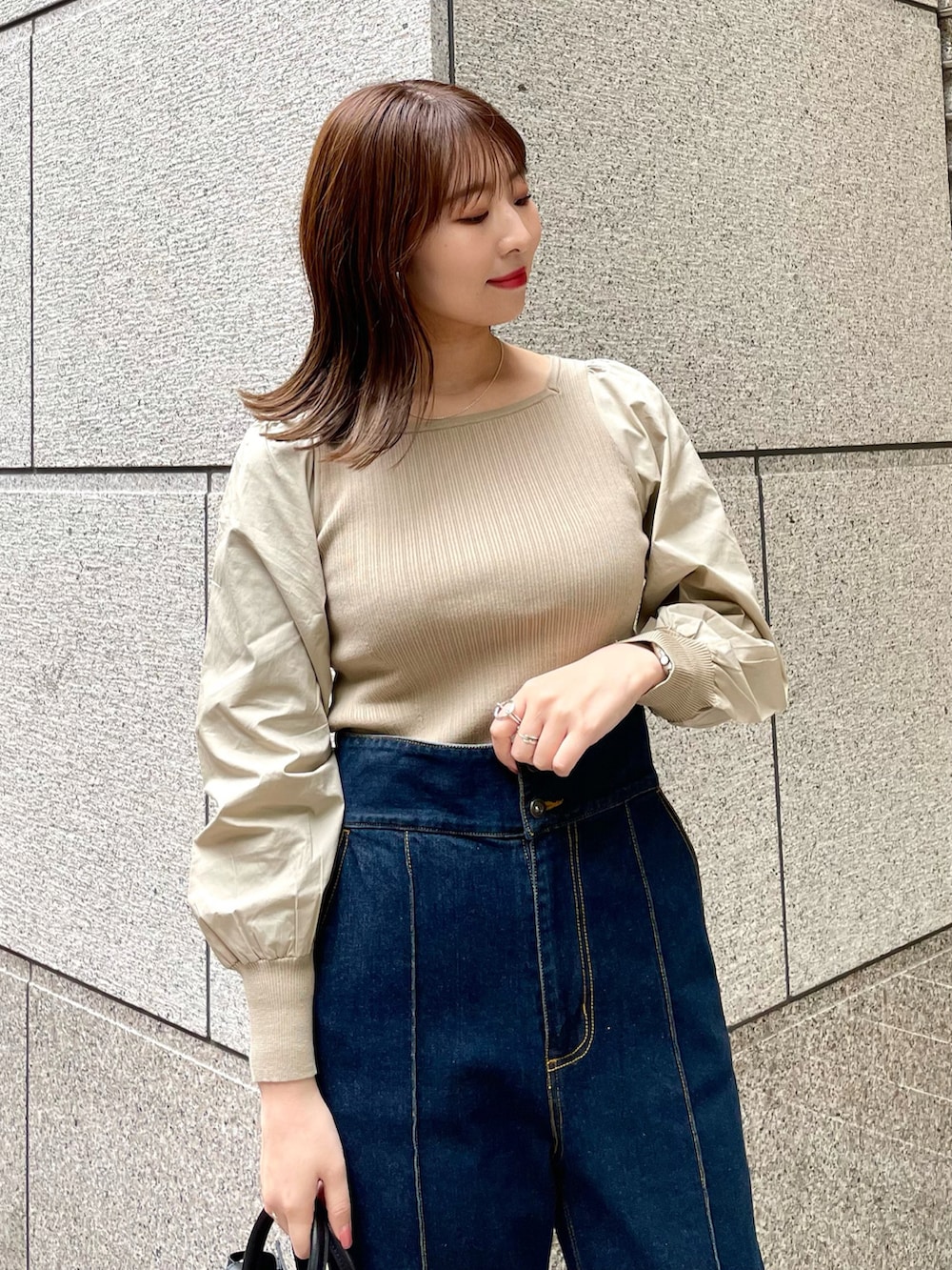 ベージュ系のニット/セーター、ブルー系のデニムパンツ、ブラック系のトートバッグを着用したレディースの春コーディネートの3枚目の写真
