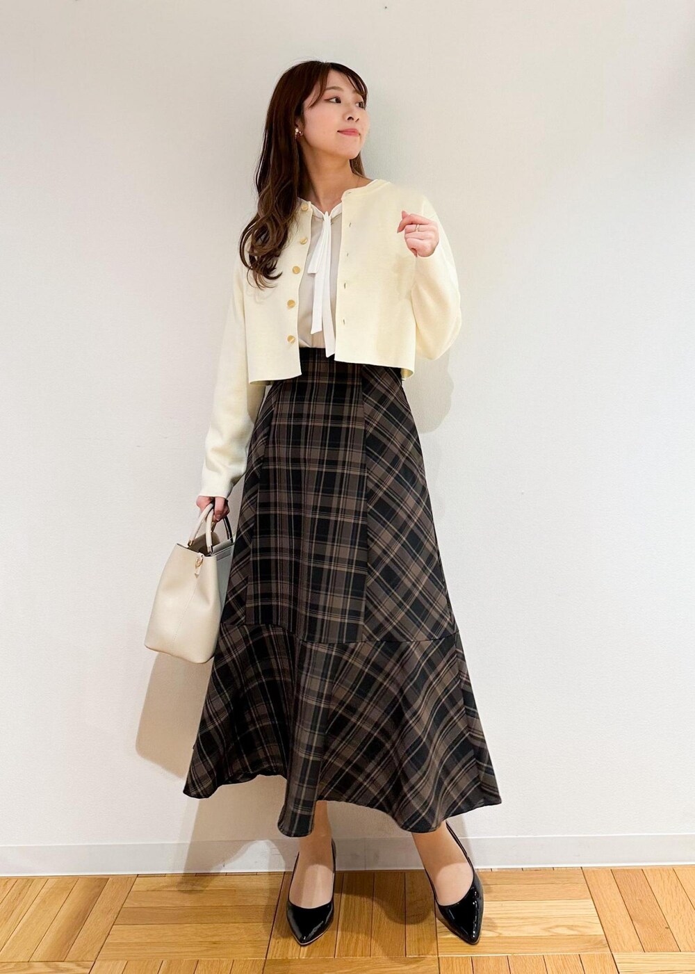 イエロー系のスカート、ベージュ系のシャツ/ブラウス、ホワイト系のカーディガン/ボレロを着用したレディースの冬コーディネートの3枚目の写真