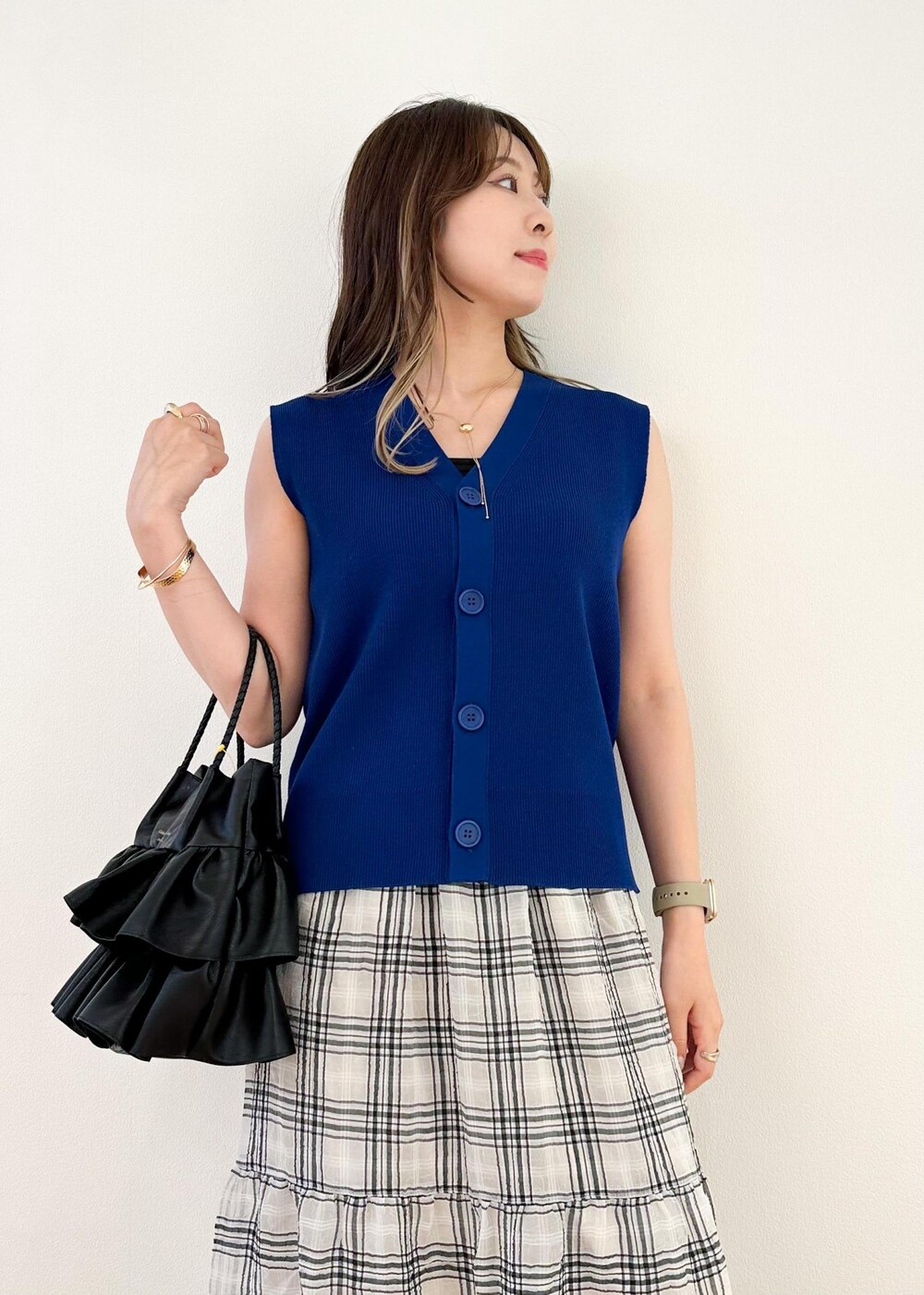 ブラック系のトートバッグ、ブルー系のベスト、ブラック系のスカートを着用したレディースの夏コーディネートの4枚目の写真