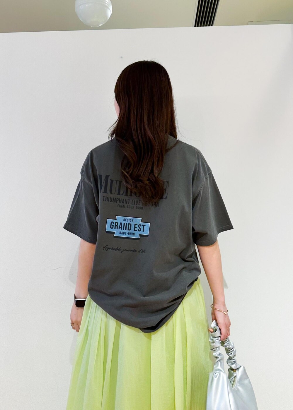 シルバー系のハンドバッグ、シルバー系のサンダル、グリーン系のスカートを着用したレディースの夏コーディネートの5枚目の写真