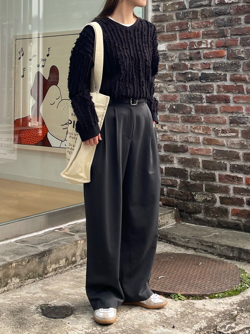 ホワイト系のトートバッグ、ブラック系のニット/セーター、ホワイト系のスニーカーを着用したレディースの春コーディネートの3枚目の写真