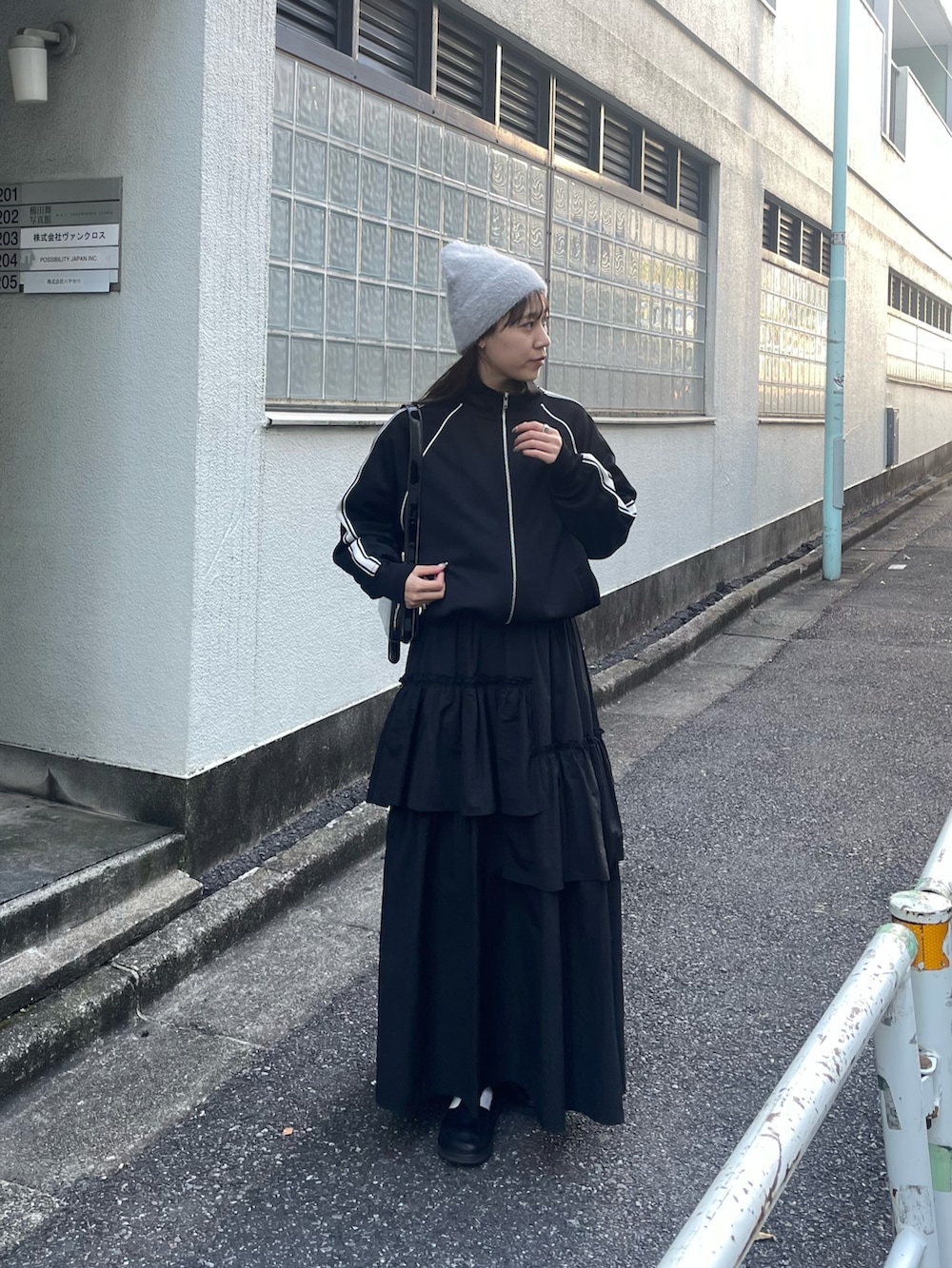 ブラック系のスカート、ブラック系のジャージ、ブラック系のショルダーバッグを着用したレディースの冬コーディネートの3枚目の写真