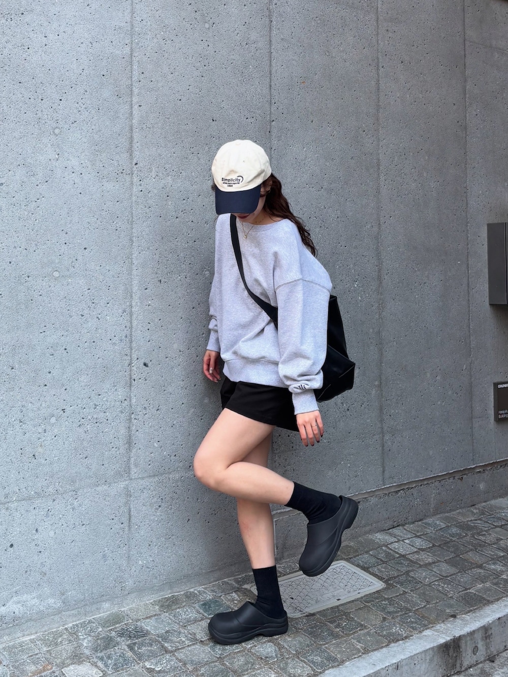 グレー系のスウェット、ブラック系のショルダーバッグ、ブラック系のレインシューズを着用したレディースの春コーディネートの3枚目の写真