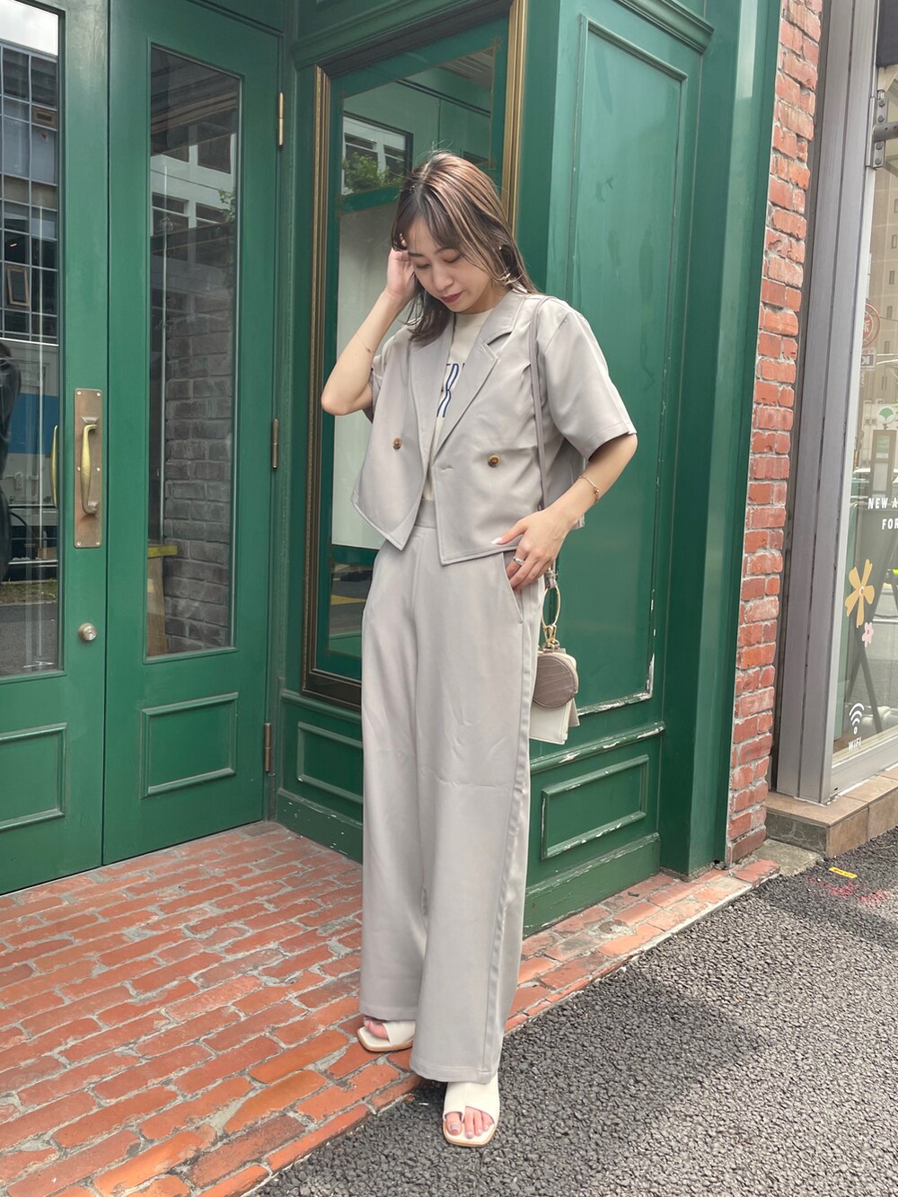 ベージュ系のセットアップ、ホワイト系のサンダル、ベージュ系のショルダーバッグを着用したレディースの夏コーディネートの2枚目の写真