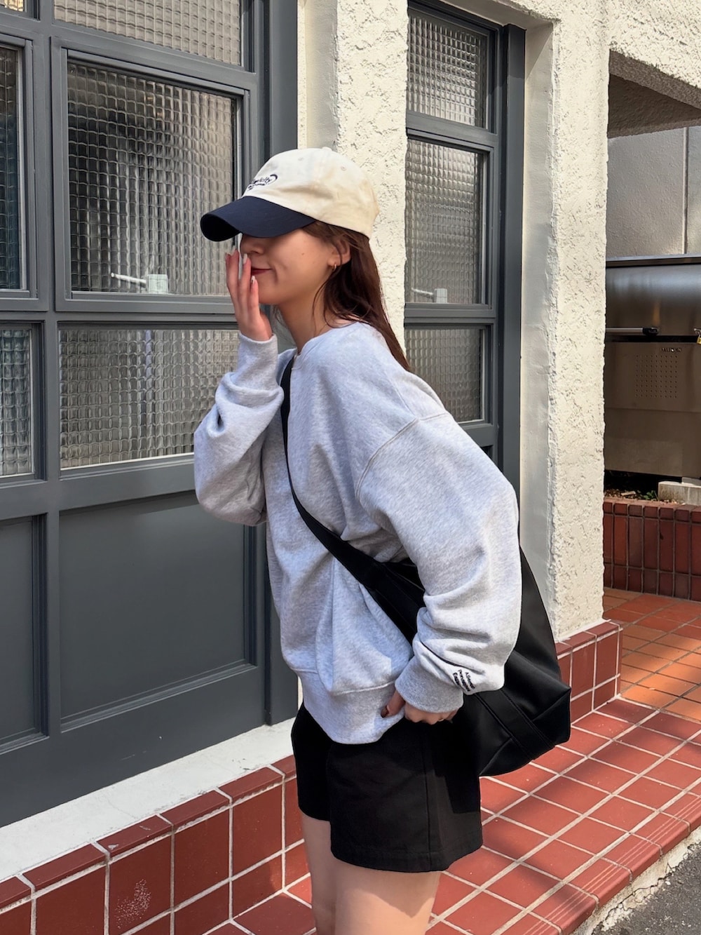 グレー系のスウェット、ブラック系のショルダーバッグ、ブラック系のレインシューズを着用したレディースの春コーディネートの5枚目の写真