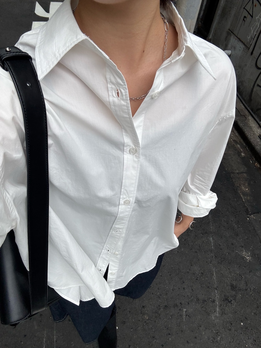 ブラック系のボディバッグ/ウエストポーチ、ホワイト系のシャツ/ブラウス、ブルー系のデニムパンツを着用したレディースの秋コーディネートの3枚目の写真