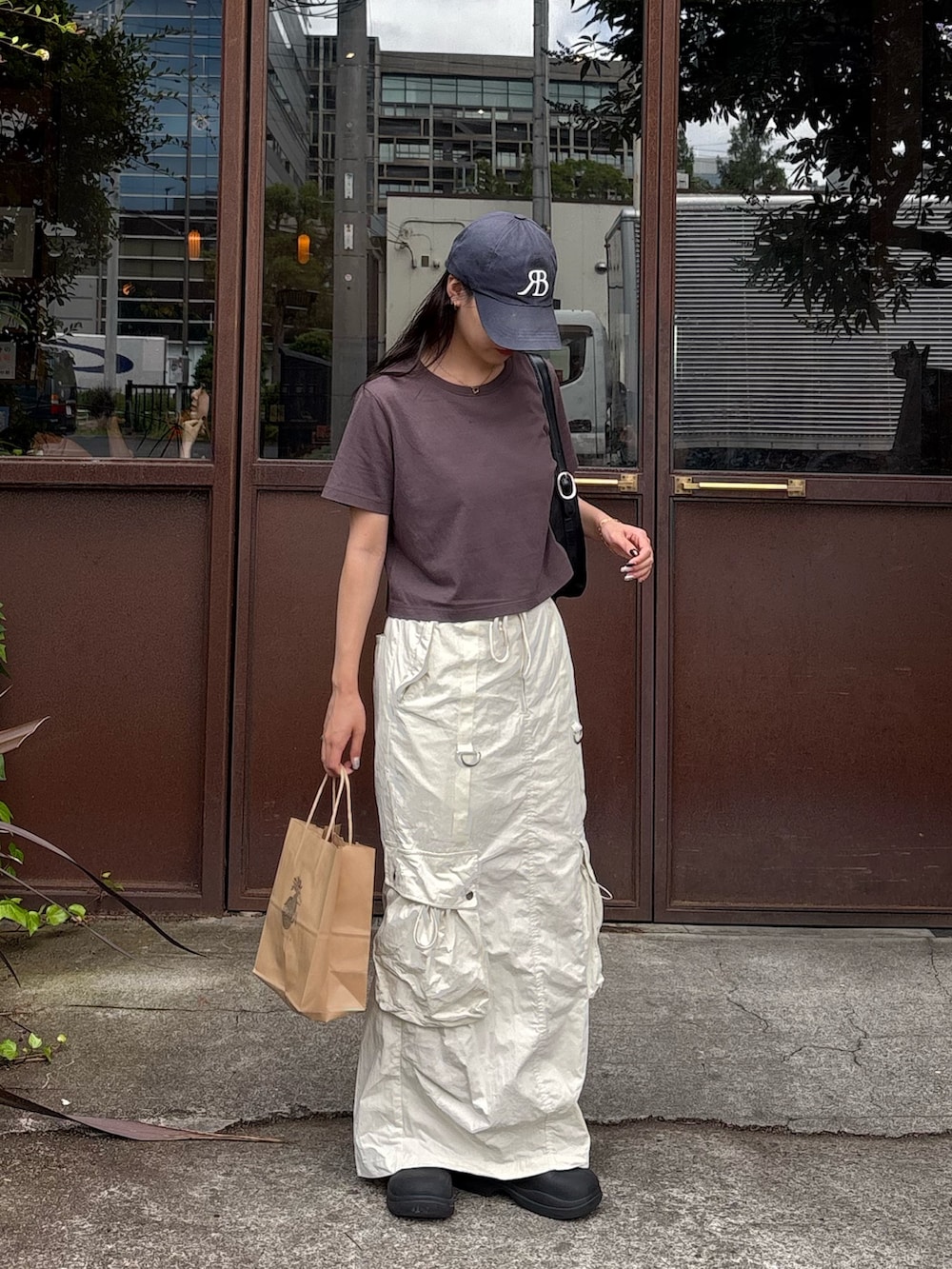 グレー系のTシャツ/カットソー、ホワイト系のスカート、ブラック系のレインシューズを着用したレディースの夏コーディネートの3枚目の写真