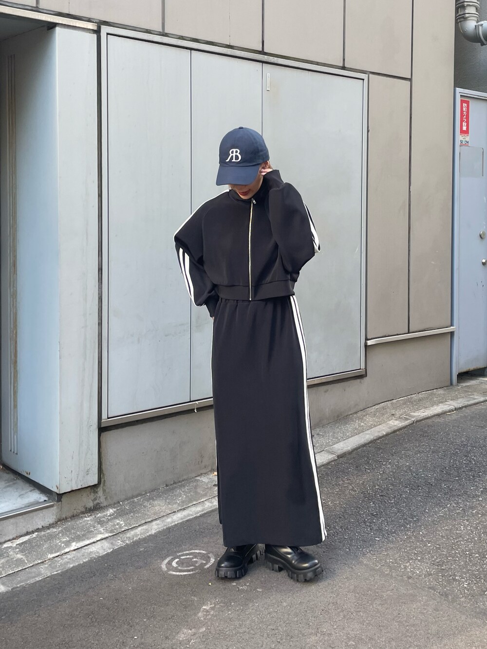 ブラック系のスカート、ブラック系のブーツ、ブラック系のジャケット/アウターを着用したレディースの夏コーディネートの2枚目の写真