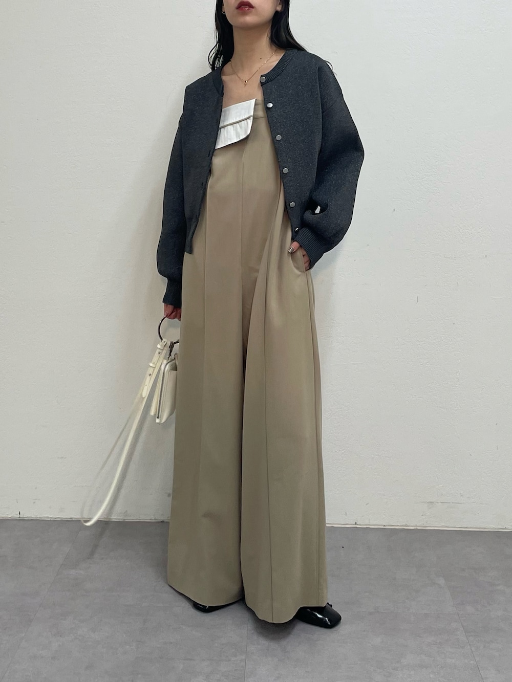 ベージュ系のつなぎ/オールインワン、グレー系のカーディガン/ボレロ、ホワイト系のショルダーバッグを着用したレディースの冬コーディネートの2枚目の写真