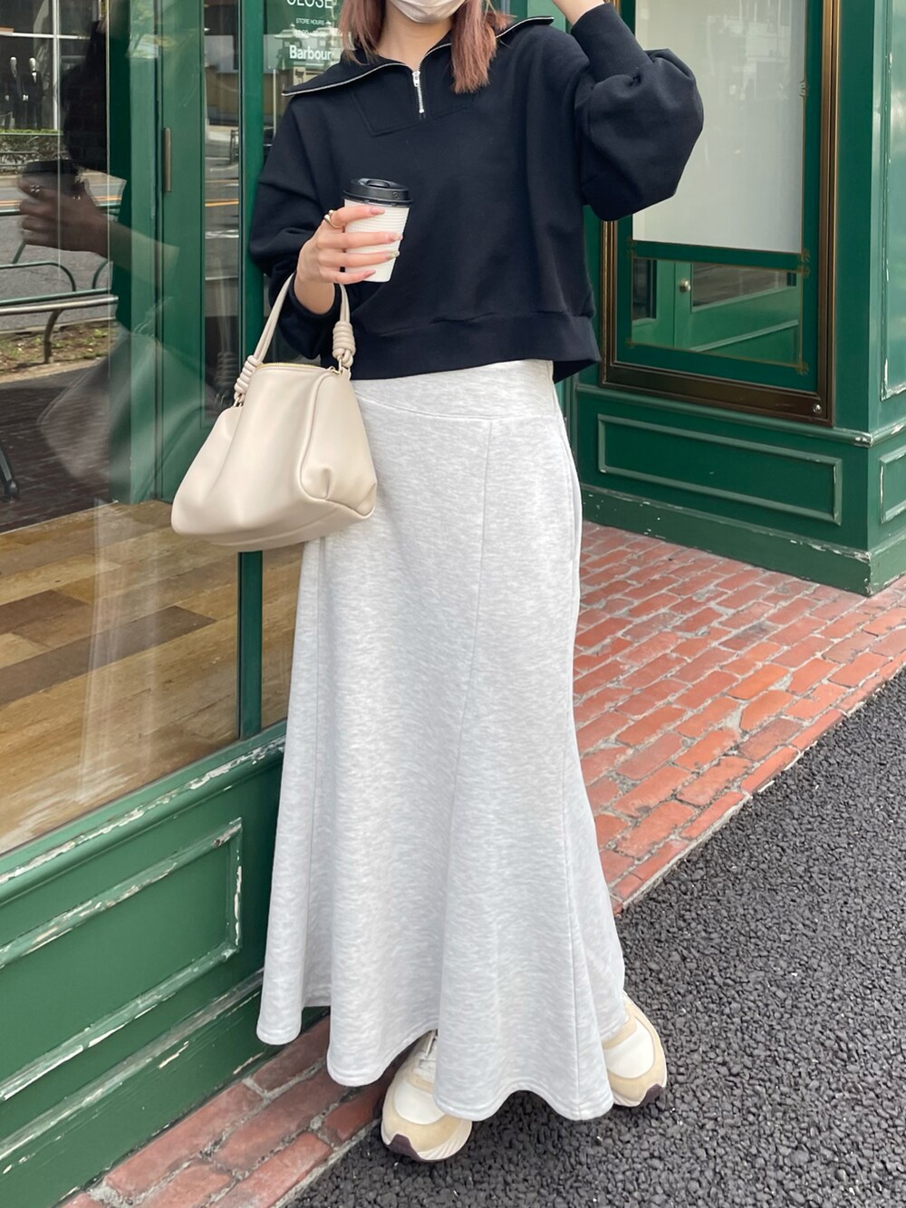 ブラック系のスウェット、ベージュ系のボストンバッグ、グレー系のスカートを着用したレディースの春コーディネートの2枚目の写真