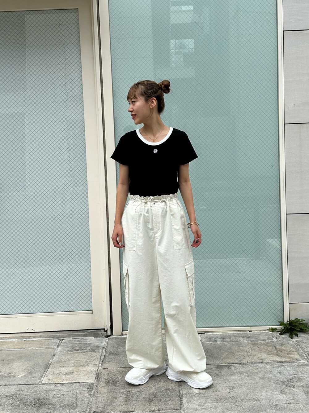 ブラック系のTシャツ/カットソー、ホワイト系のカーゴパンツ、ホワイト系のスニーカーを着用したレディースの夏コーディネートの2枚目の写真