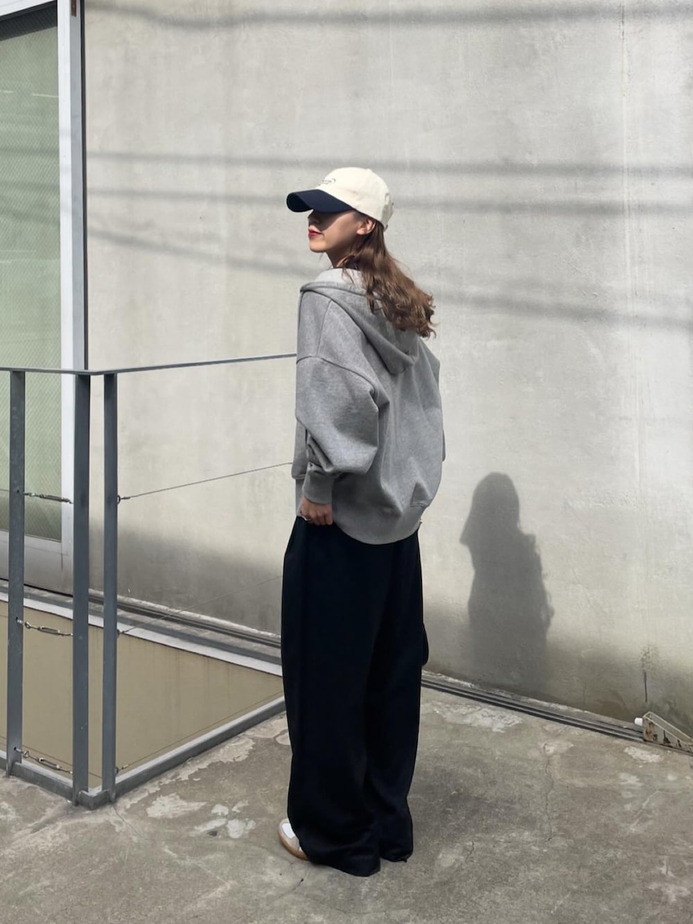グレー系のパーカー、ホワイト系のスニーカーを着用したレディースの春コーディネートの2枚目の写真