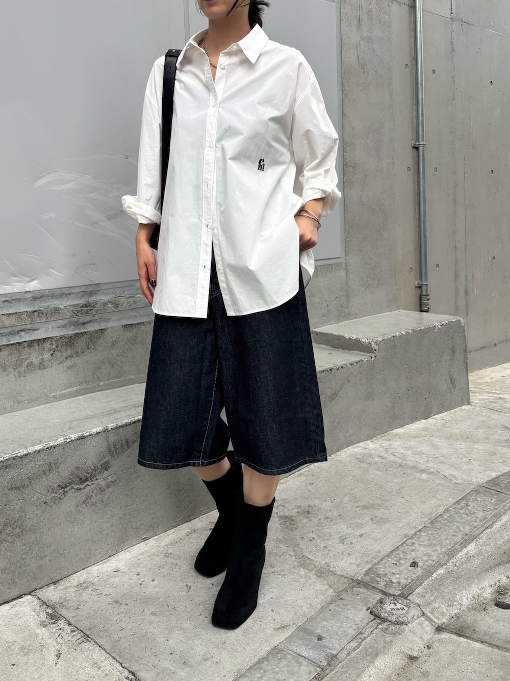 ブラック系のボディバッグ/ウエストポーチ、ホワイト系のシャツ/ブラウス、ブルー系のデニムパンツを着用したレディースの秋コーディネートの4枚目の写真