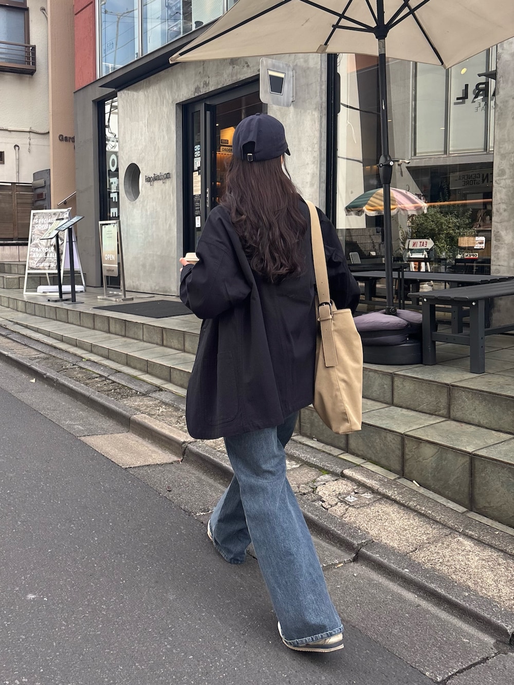 ブルー系のデニムパンツ、ベージュ系のショルダーバッグ、ブラック系のTシャツ/カットソーを着用したレディースの冬コーディネートの4枚目の写真