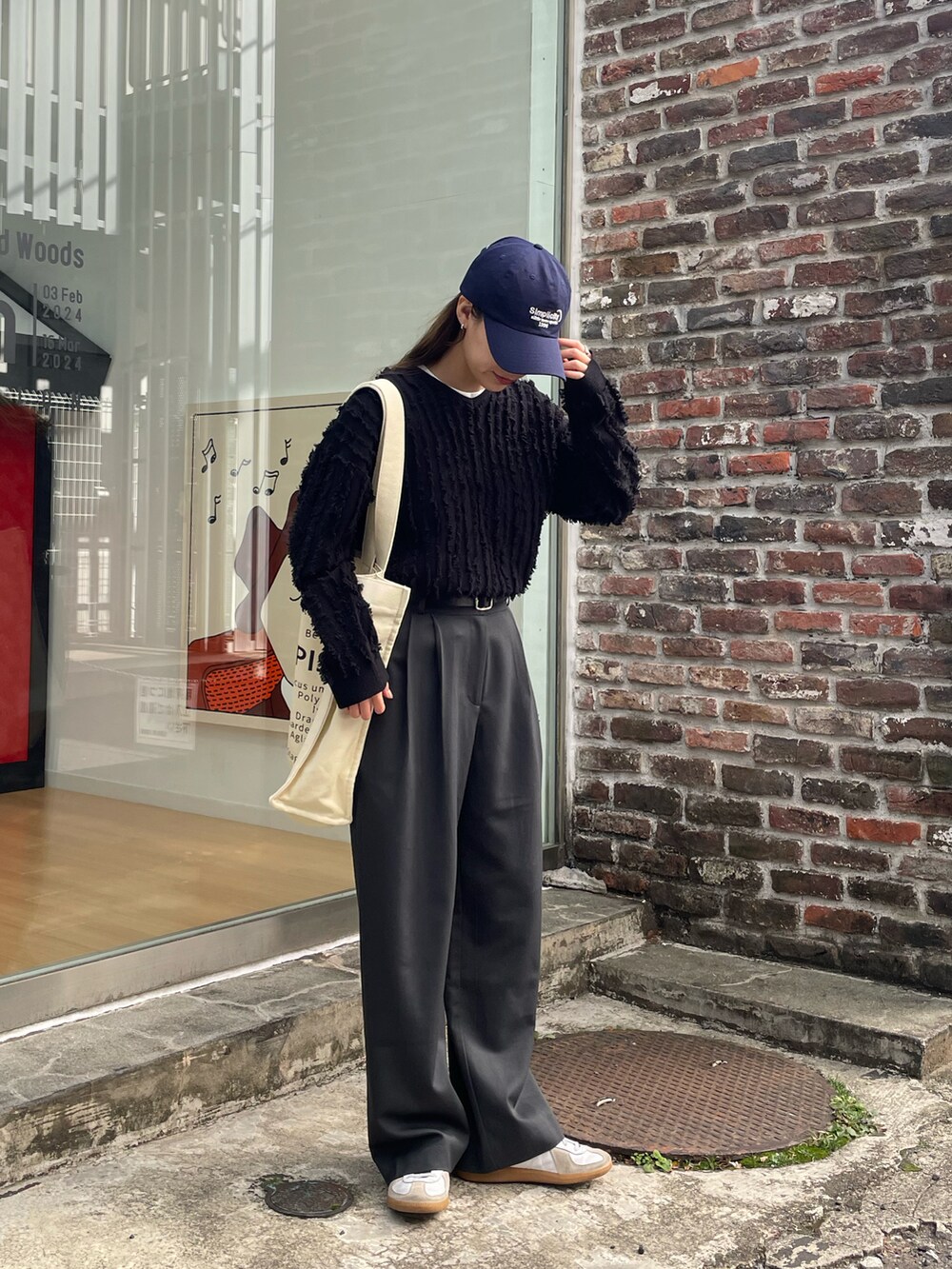 ホワイト系のトートバッグ、ブラック系のニット/セーター、ホワイト系のスニーカーを着用したレディースの春コーディネートの4枚目の写真
