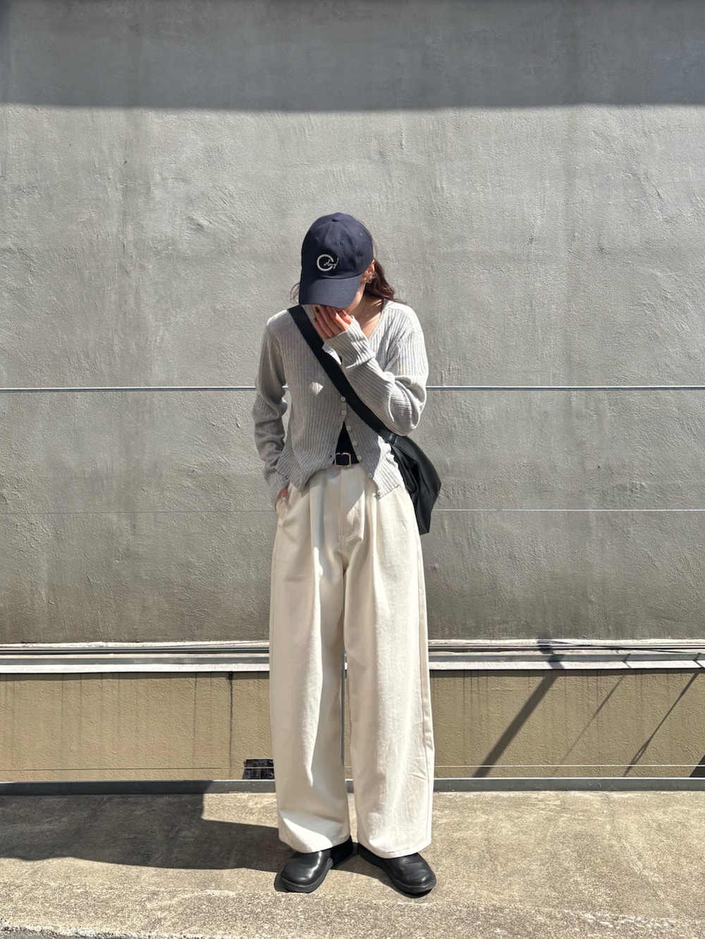 ホワイト系のその他パンツ、グレー系のカーディガン/ボレロ、ブラック系のショルダーバッグを着用したレディースの春コーディネートの3枚目の写真