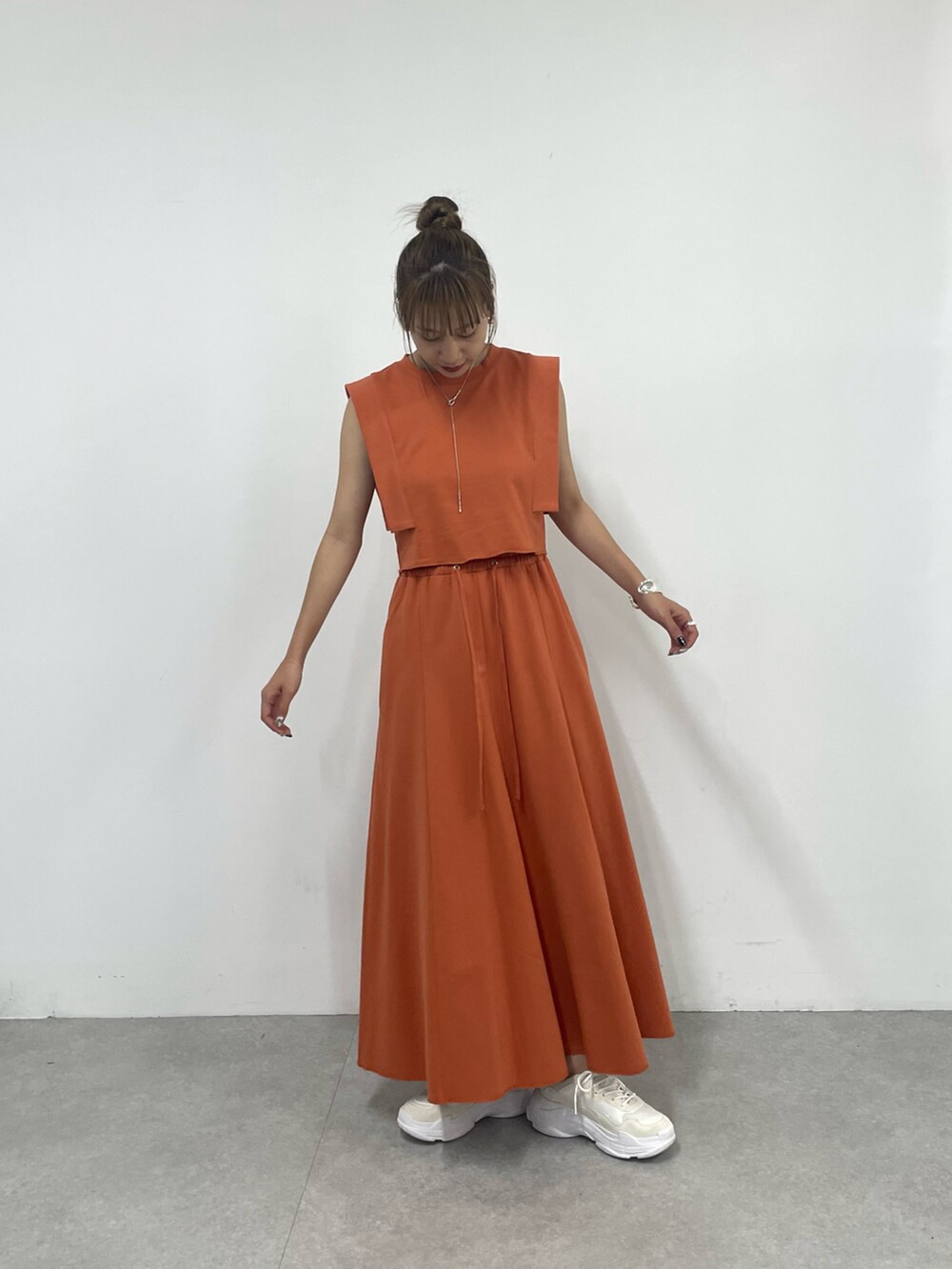 ホワイト系のスニーカー、オレンジ系のワンピース、シルバー系のネックレスを着用したレディースの夏コーディネートの3枚目の写真