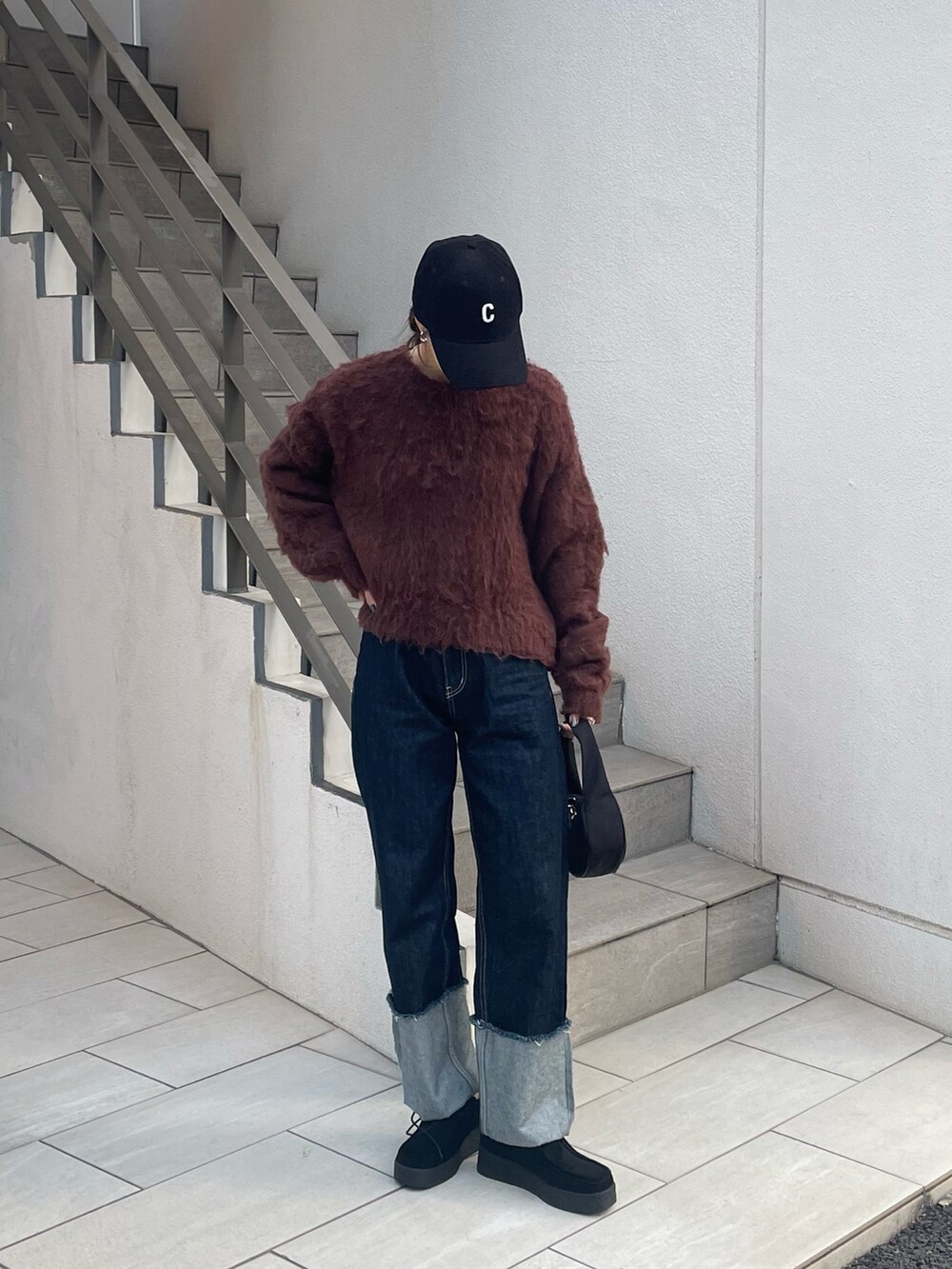 ブルー系のデニムパンツ、ブラウン系のニット/セーター、ブラック系のモカシン/デッキシューズを着用したレディースの秋コーディネートの3枚目の写真