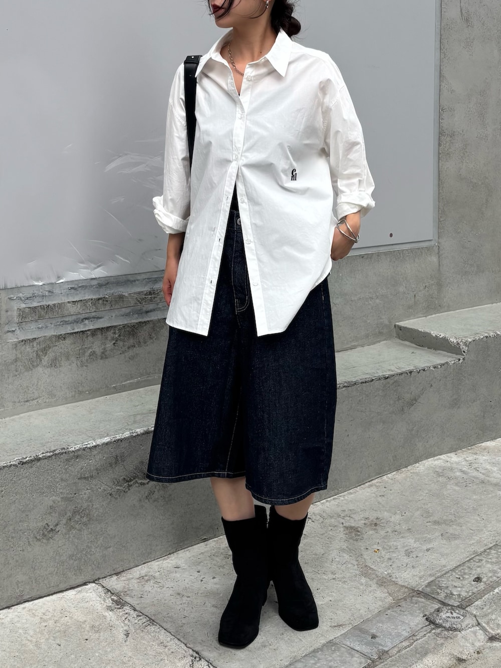 ブラック系のボディバッグ/ウエストポーチ、ホワイト系のシャツ/ブラウス、ブルー系のデニムパンツを着用したレディースの秋コーディネートの2枚目の写真