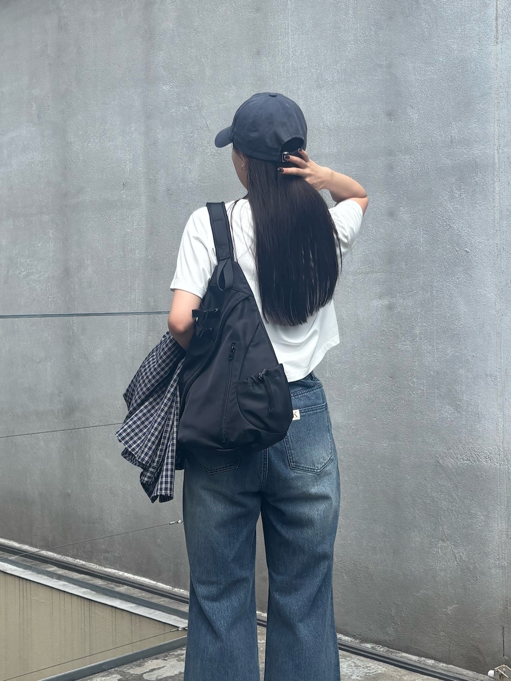 ブルー系のデニムパンツ、ホワイト系のTシャツ/カットソー、ブラック系のボディバッグ/ウエストポーチを着用したレディースの秋コーディネートの3枚目の写真