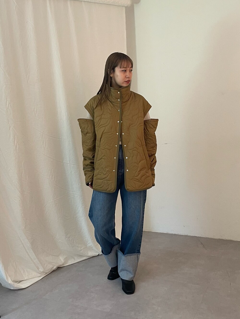 ブルー系のデニムパンツ、グリーン系のブルゾン、ブラック系のブーツを着用したレディースの夏コーディネートの2枚目の写真