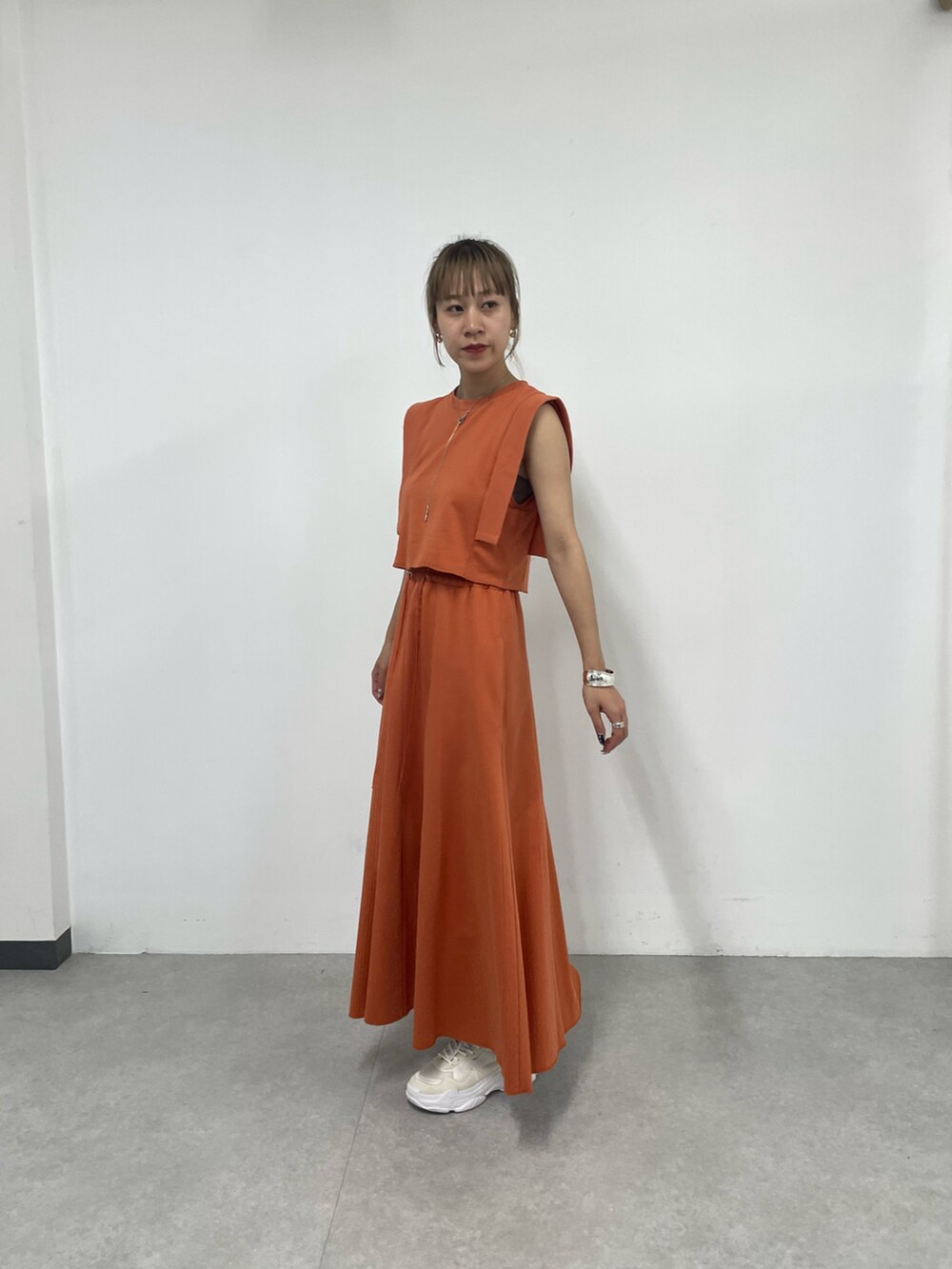 ホワイト系のスニーカー、オレンジ系のワンピース、シルバー系のネックレスを着用したレディースの夏コーディネートの2枚目の写真