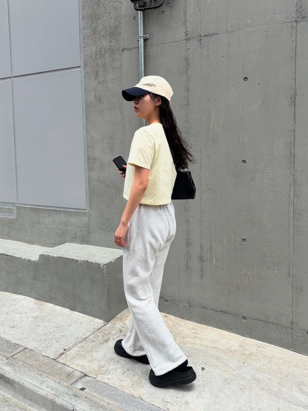 イエロー系のTシャツ/カットソー、ホワイト系のスウェットパンツ、ブラック系のレインシューズを着用したレディースの夏コーディネートの3枚目の写真