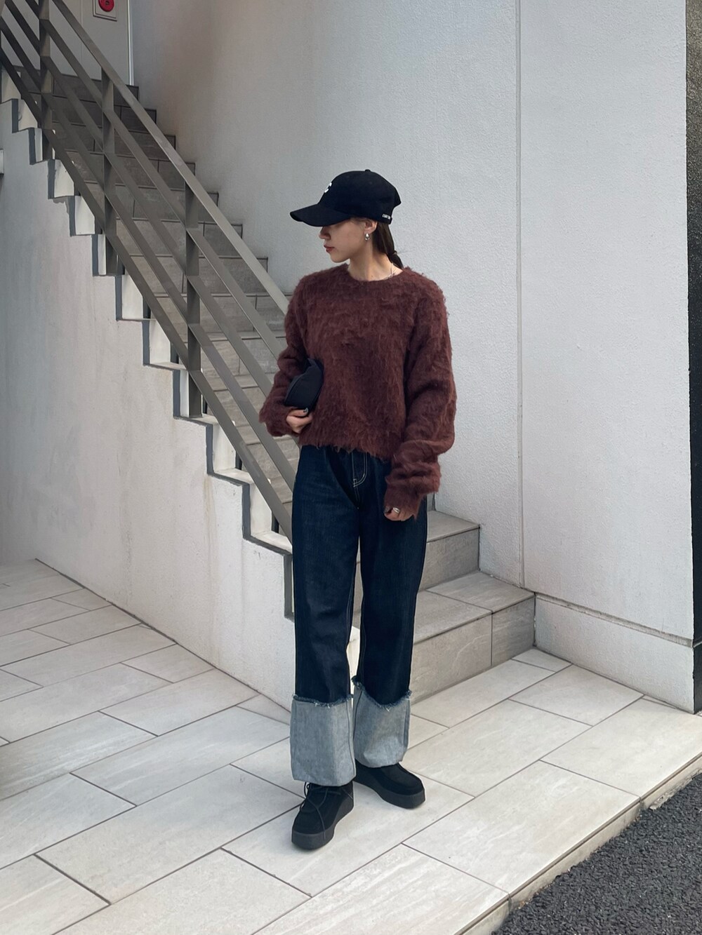 ブルー系のデニムパンツ、ブラウン系のニット/セーター、ブラック系のモカシン/デッキシューズを着用したレディースの秋コーディネートの2枚目の写真