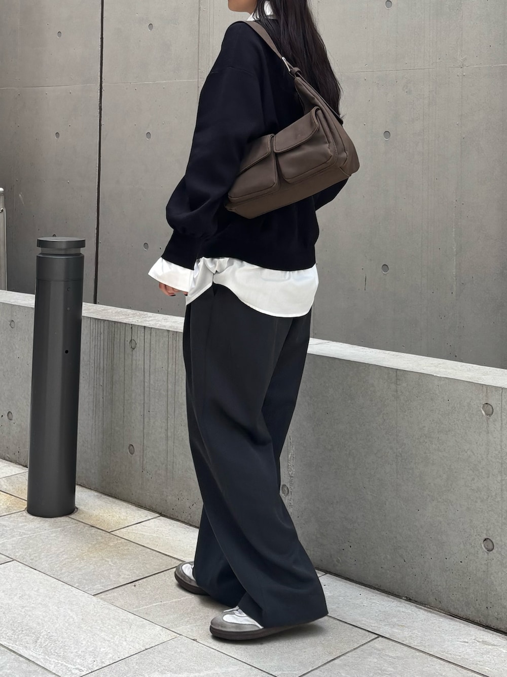 ブラック系のニット/セーター、グレー系のスラックス、ブラウン系のショルダーバッグを着用したレディースの冬コーディネートの3枚目の写真