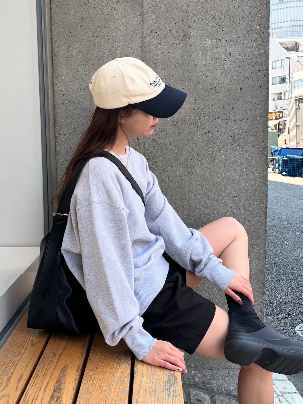 グレー系のスウェット、ブラック系のショルダーバッグ、ブラック系のレインシューズを着用したレディースの春コーディネートの2枚目の写真