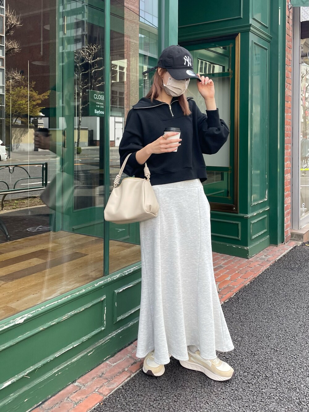 ブラック系のスウェット、ベージュ系のボストンバッグ、グレー系のスカートを着用したレディースの春コーディネートの3枚目の写真