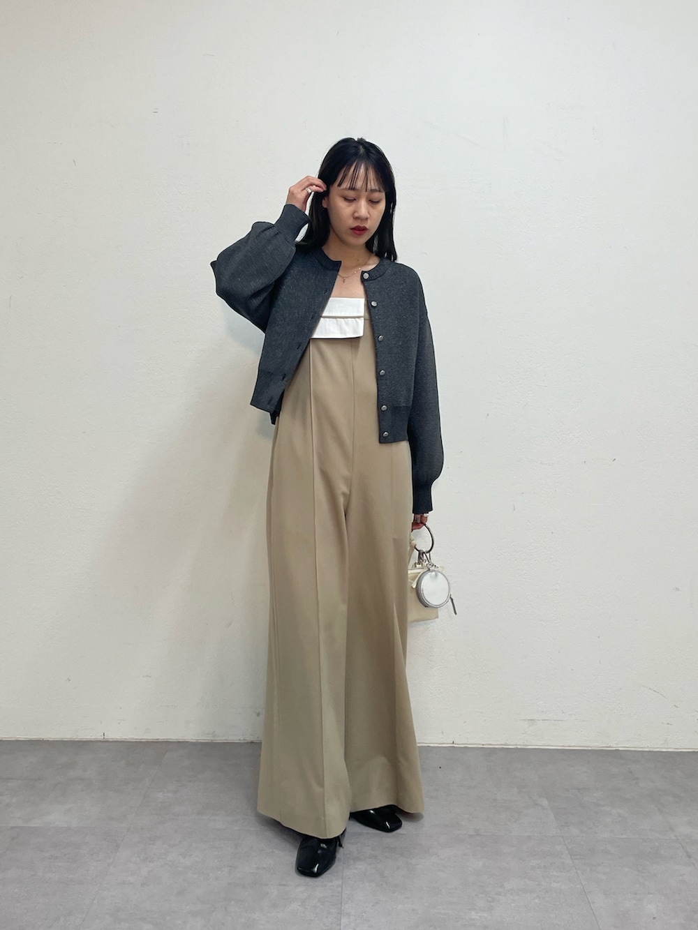 ベージュ系のつなぎ/オールインワン、グレー系のカーディガン/ボレロ、ホワイト系のショルダーバッグを着用したレディースの冬コーディネートの4枚目の写真