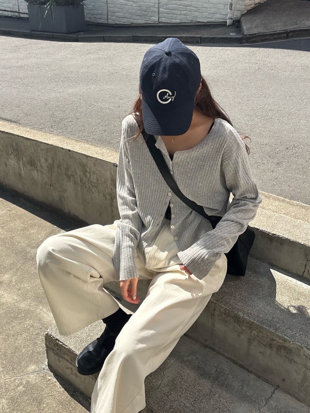 ホワイト系のその他パンツ、グレー系のカーディガン/ボレロ、ブラック系のショルダーバッグを着用したレディースの春コーディネートの2枚目の写真