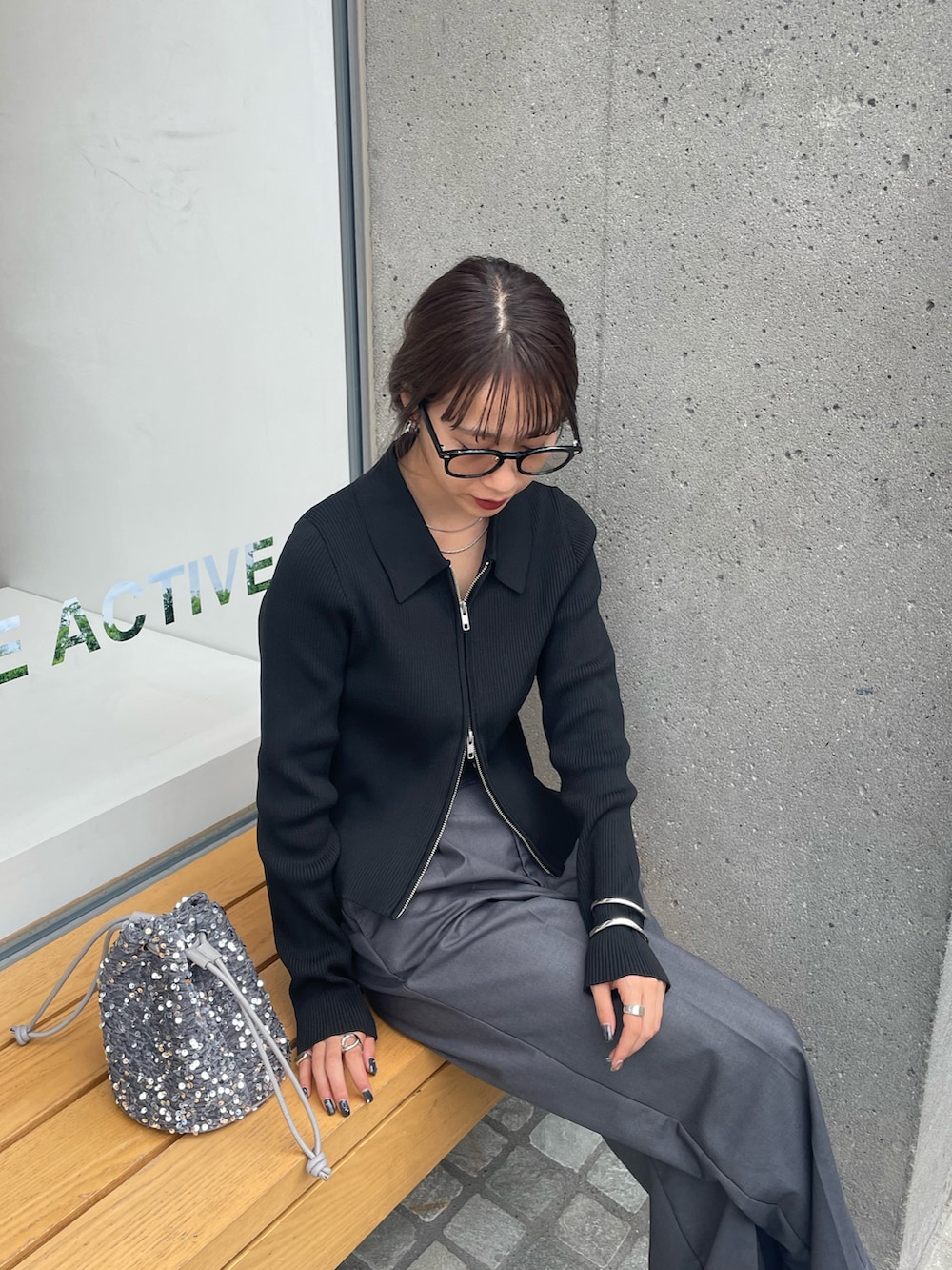 グレー系のスラックス、シルバー系のショルダーバッグ、ホワイト系のスニーカーを着用したレディースの秋コーディネートの2枚目の写真