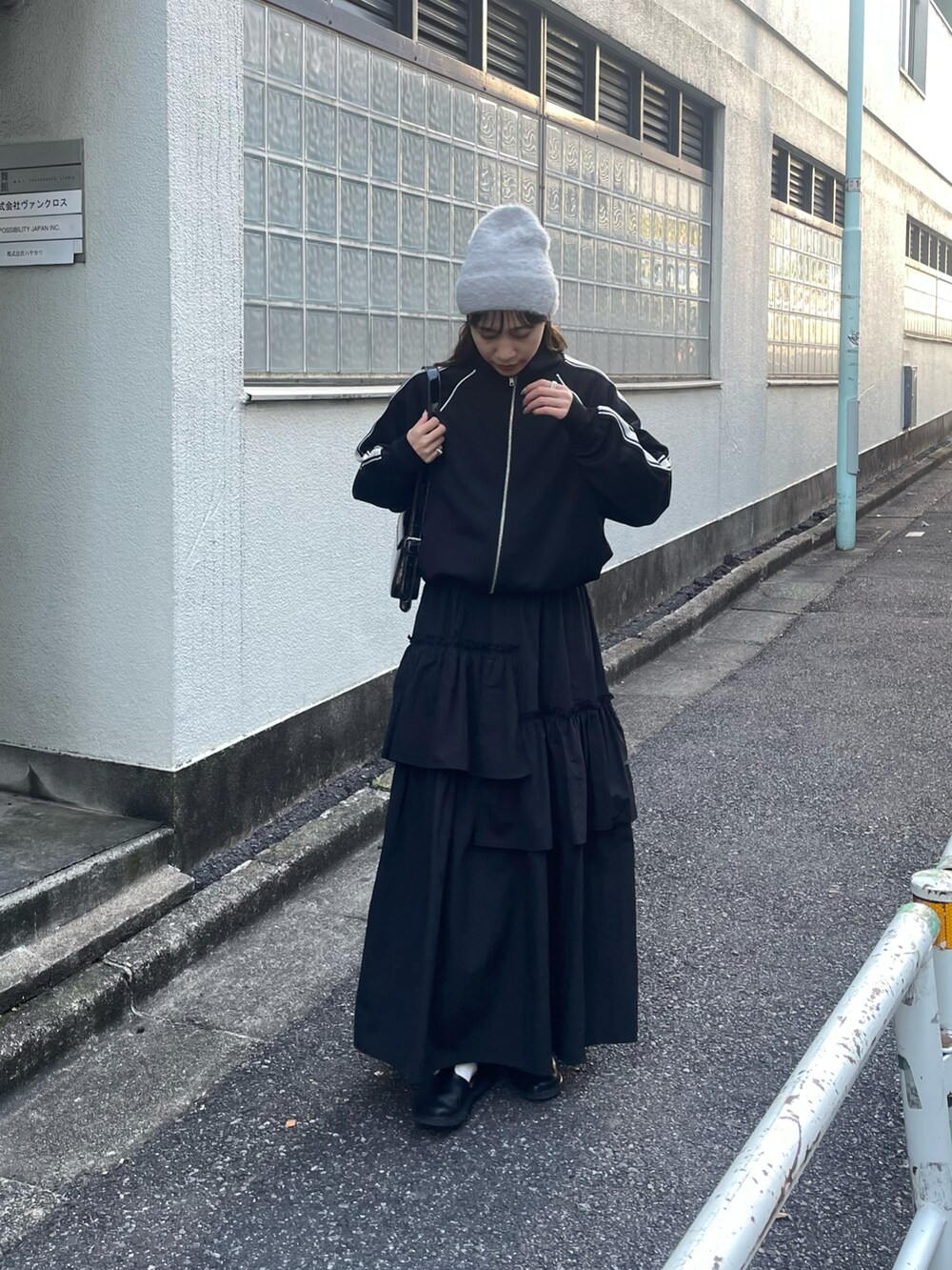 ブラック系のスカート、ブラック系のジャージ、ブラック系のショルダーバッグを着用したレディースの冬コーディネートの2枚目の写真