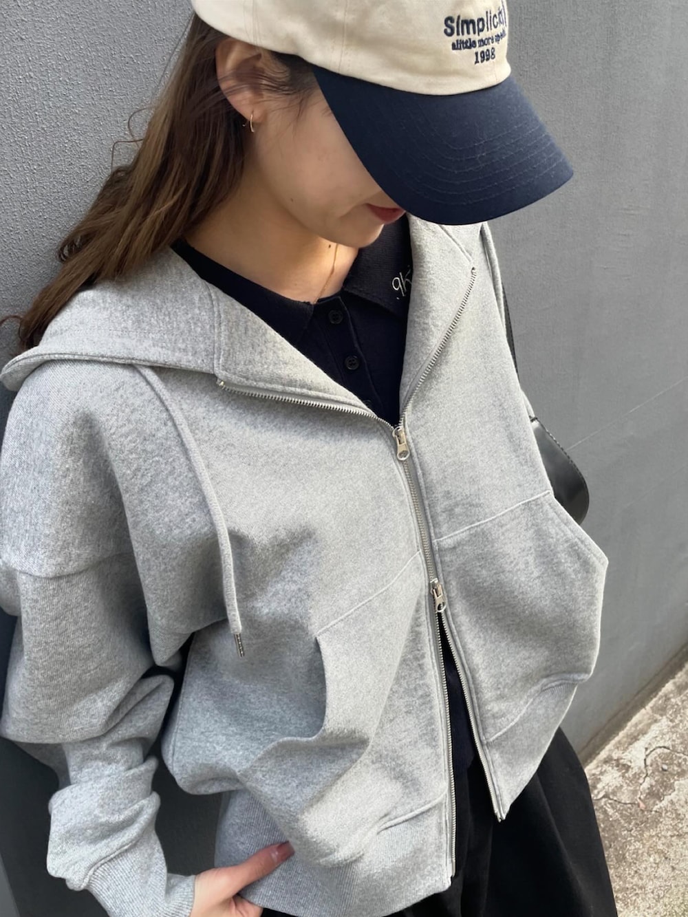 グレー系のパーカー、ホワイト系のスニーカーを着用したレディースの春コーディネートの3枚目の写真