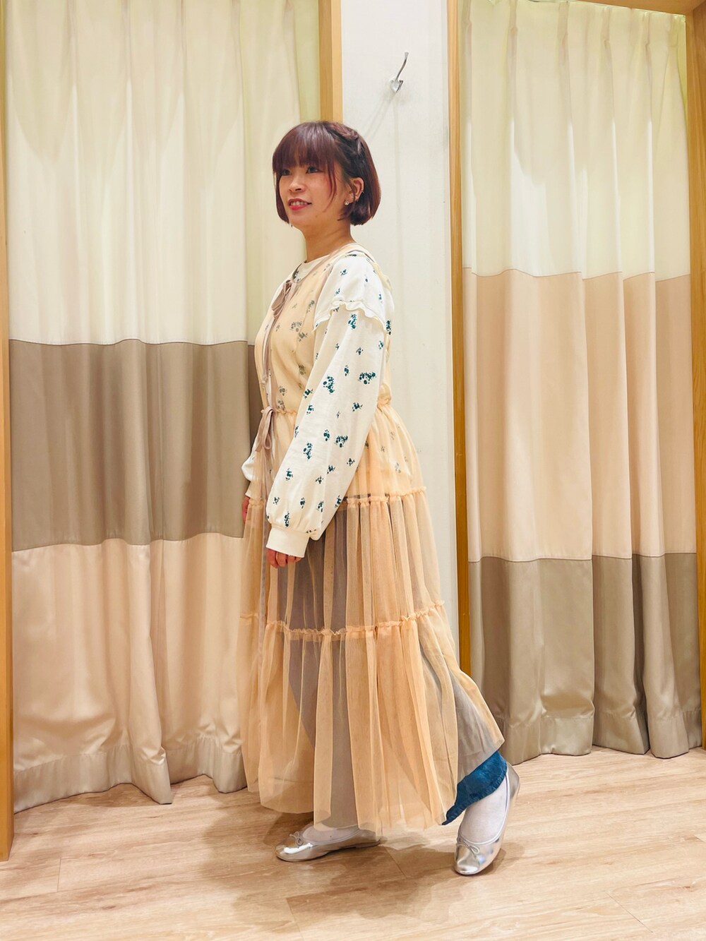 グリーン系のTシャツ/カットソー、オレンジ系のワンピース、ブルー系のデニムパンツを着用したレディースの春コーディネートの2枚目の写真