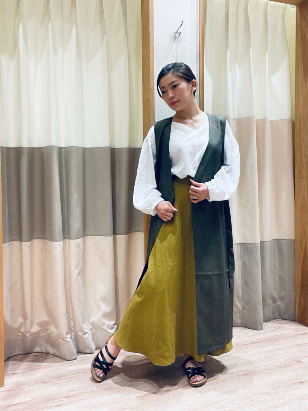 ホワイト系のシャツ/ブラウス、イエロー系のスカート、ブラック系のサンダルを着用したレディースの夏コーディネートの2枚目の写真