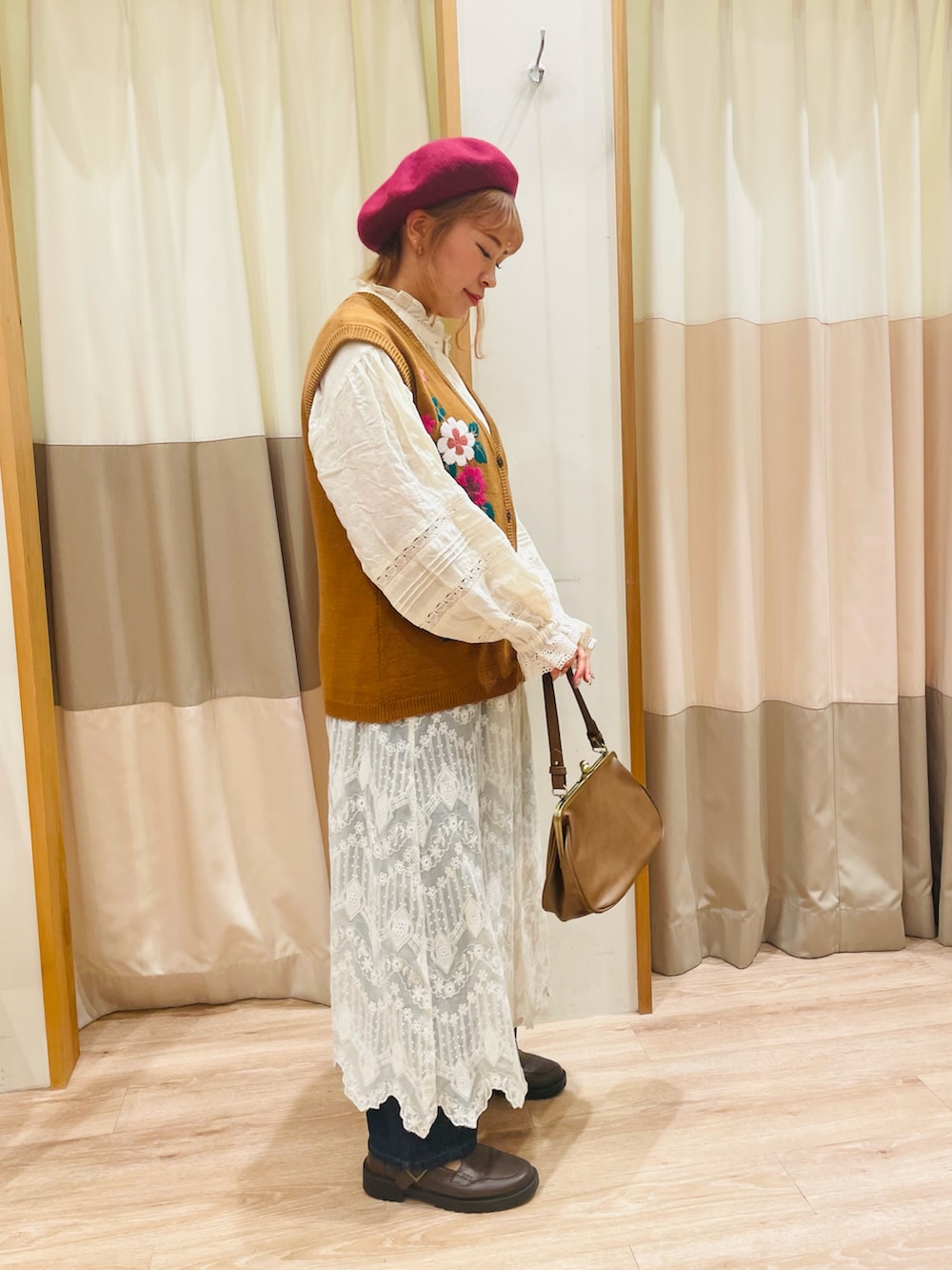 イエロー系のベスト、ホワイト系のシャツ/ブラウス、ブラウン系のハンドバッグを着用したレディースの秋コーディネートの2枚目の写真