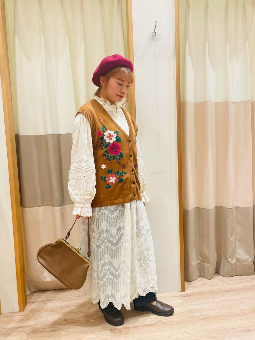 イエロー系のベスト、ホワイト系のシャツ/ブラウス、ブラウン系のハンドバッグを着用したレディースの秋コーディネートの3枚目の写真