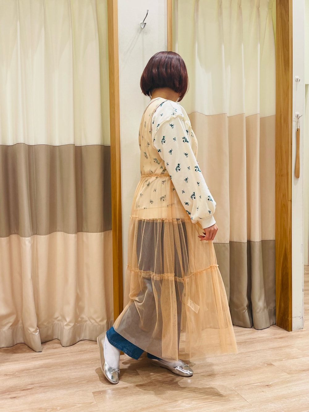 グリーン系のTシャツ/カットソー、オレンジ系のワンピース、ブルー系のデニムパンツを着用したレディースの春コーディネートの4枚目の写真