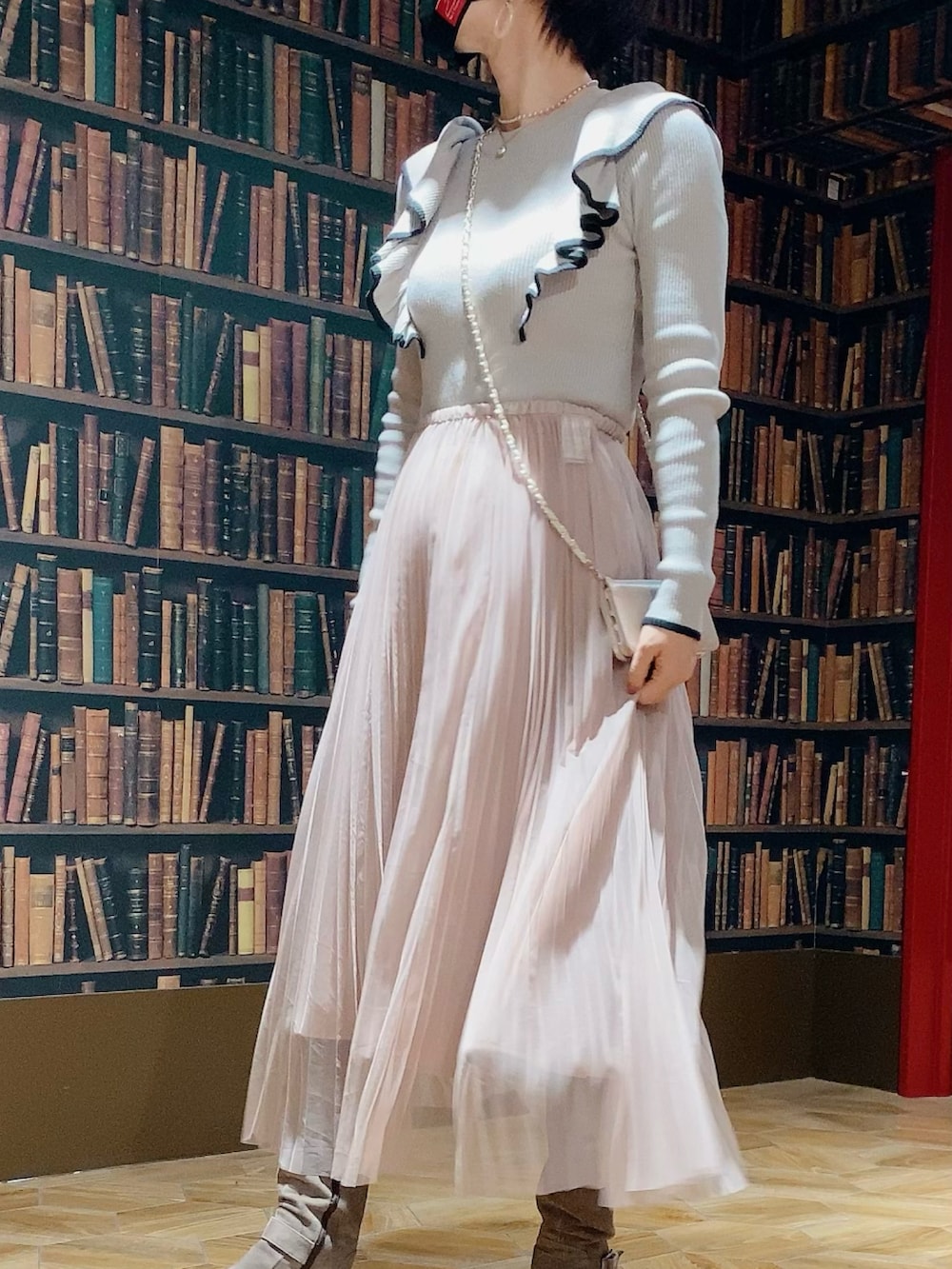 ピンク系のスカート、グレー系のブーツ、グレー系のハンドバッグを着用したレディースの冬コーディネートの2枚目の写真