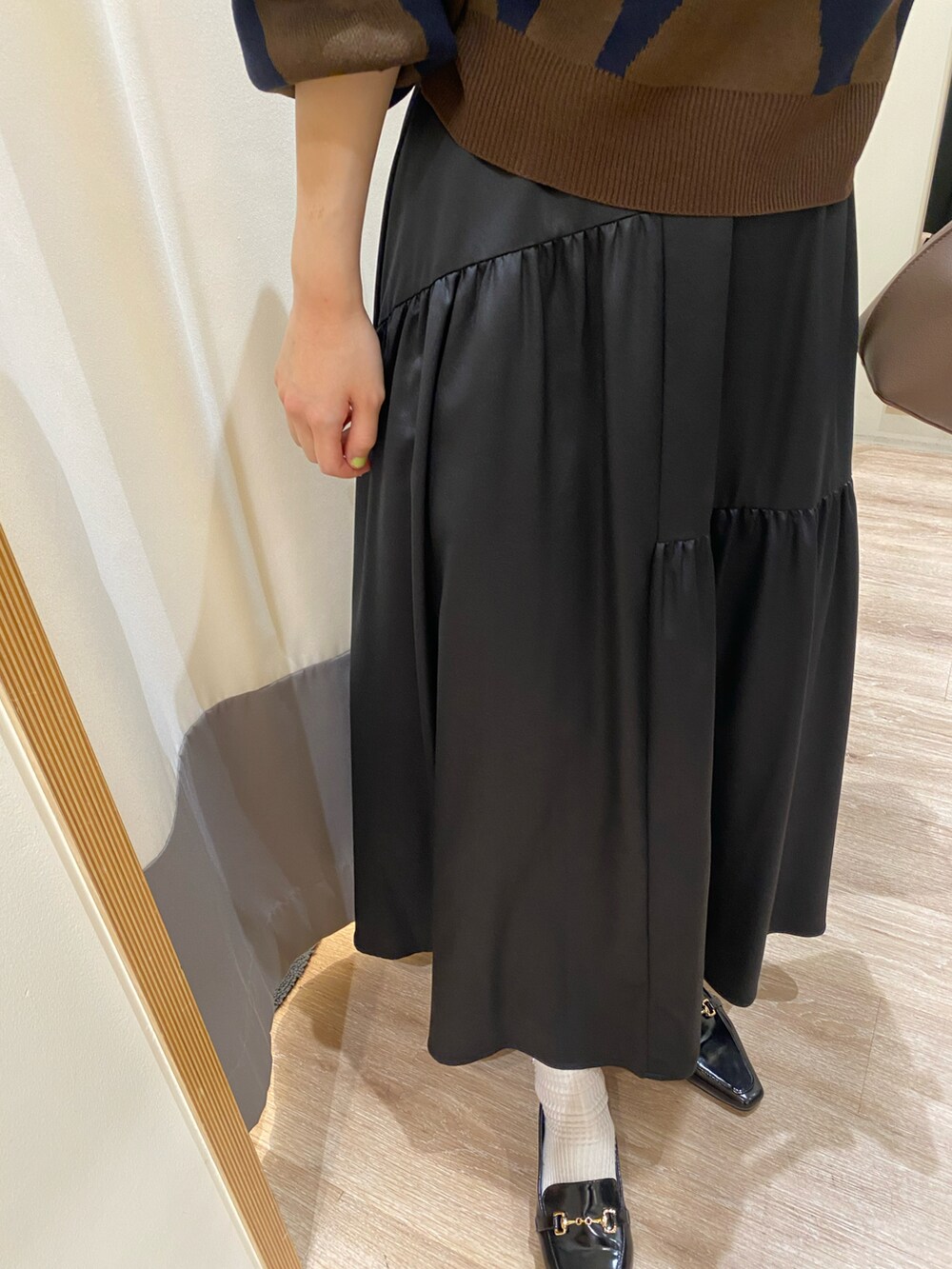 ブラック系のローファー、ブラック系のスカート、ブラウン系のハンドバッグを着用したレディースの秋コーディネートの3枚目の写真