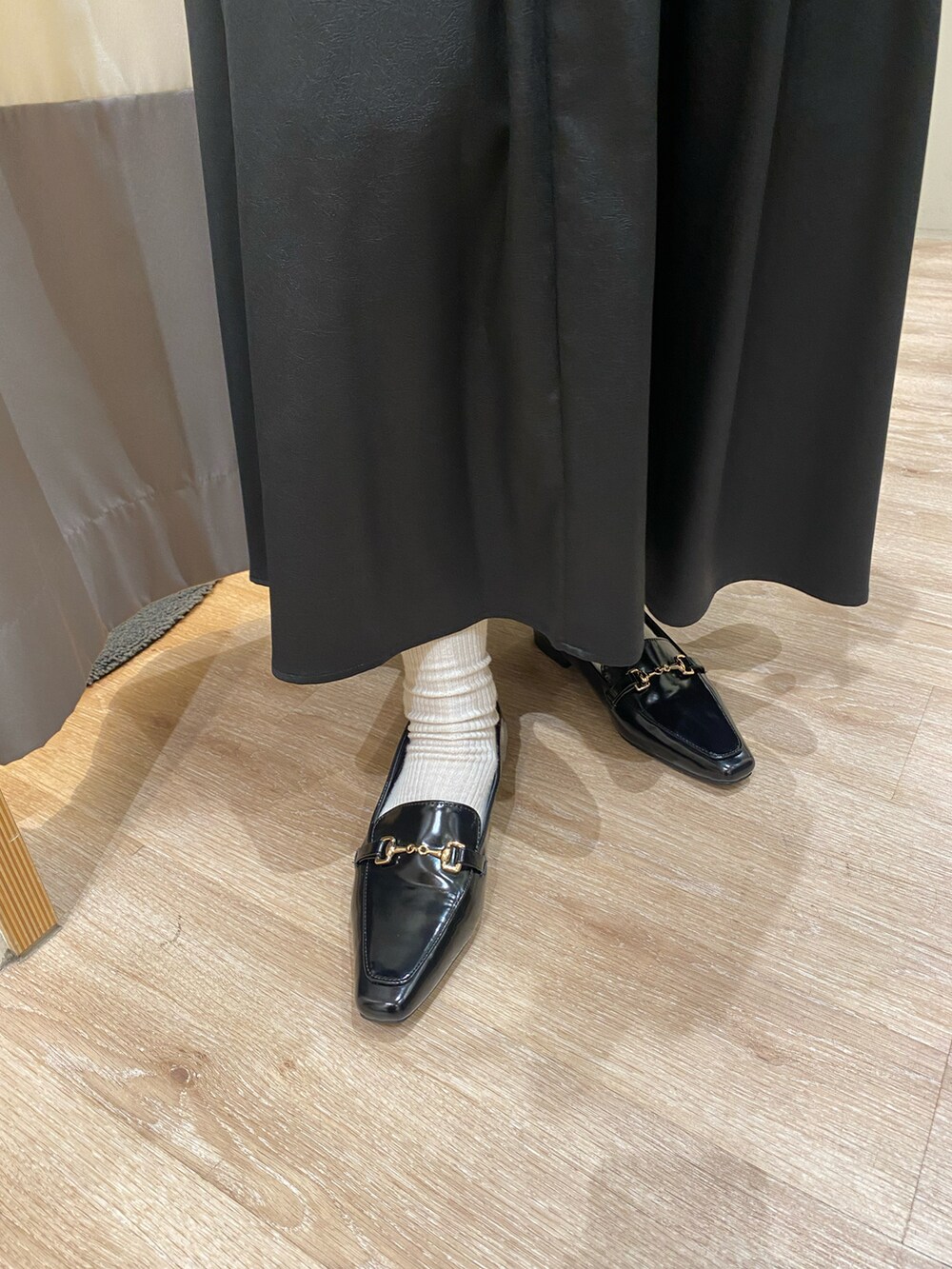 ブラック系のローファー、ブラック系のスカート、ブラウン系のハンドバッグを着用したレディースの秋コーディネートの5枚目の写真